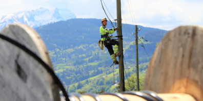 In luftiger Höhe wird das Freileitungsrohr für die Glasfasern an die bestehenden Masten angebracht. 