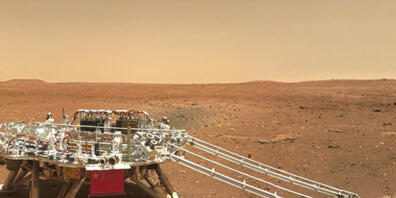 Auf dem Foto der China National Space Administration (CNSA) vom Freitag ist rechts von der Landeplattform deutlich die Spur zu sehen, welche der Rover Zhurong beim Wenden im Marssand gelegt hat. China freut sich, einen sichtbaren Eindruck auf dem ...
