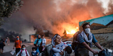 ARCHIV - Migranten fliehen vor einem erneuten Feuers mit ihren Habseligkeiten aus dem Flüchtlingslager Moria. Foto: Petros Giannakouris/AP/dpa