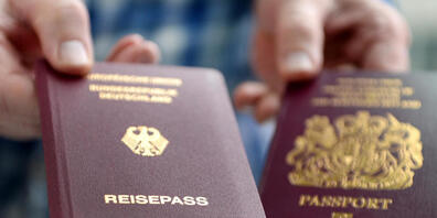 ARCHIV - Ein britischer und ein deutscher Reisepass werden in die Kamera gehalten. Foto: Britta Pedersen/zb/dpa