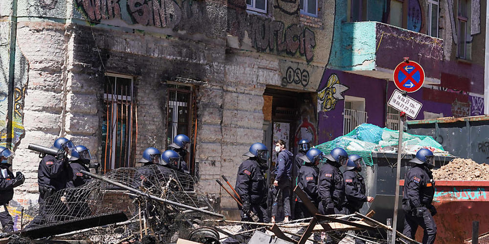 Polizisten gehen in der Rigaer Straße in Berlin-Friedrichshain mit einemn Rammbock neben einer Barrikade entlang. Foto: Jörg Carstensen/dpa