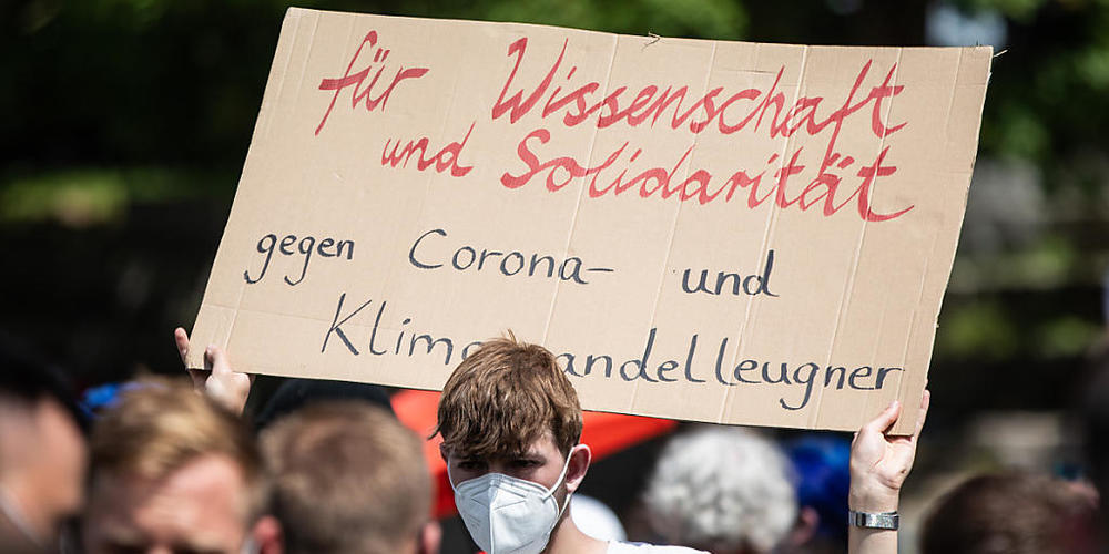 «Für Wissenschaft und Solidarität - Gegen Corona- und Klimawandelleugner» steht auf dem Schild eines Demonstranten, der an einer Gegen-Demonstration teilnimmt, die sich gegen die Demo der Initiative «Querdenken» richtet. Foto: Christoph Schmidt/dpa