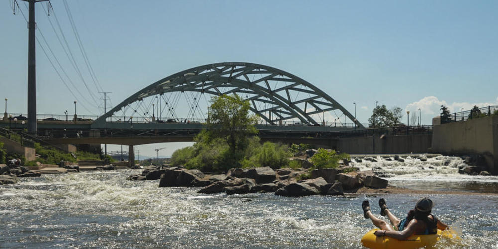 Menschen kühlen sich im Wasser ab, am Zusammenfluss von South Platte River und Cherry Creek. Am Nachmittag erreichte die Temperatur 35 Grad Celsius als Teil der Hitzewelle, die über den Westen der USA hinwegfegt. Foto: Brittany Peterson/AP/dpa
