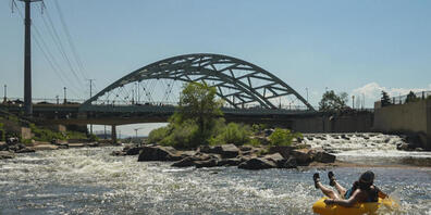 Menschen kühlen sich im Wasser ab, am Zusammenfluss von South Platte River und Cherry Creek. Am Nachmittag erreichte die Temperatur 35 Grad Celsius als Teil der Hitzewelle, die über den Westen der USA hinwegfegt. Foto: Brittany Peterson/AP/dpa