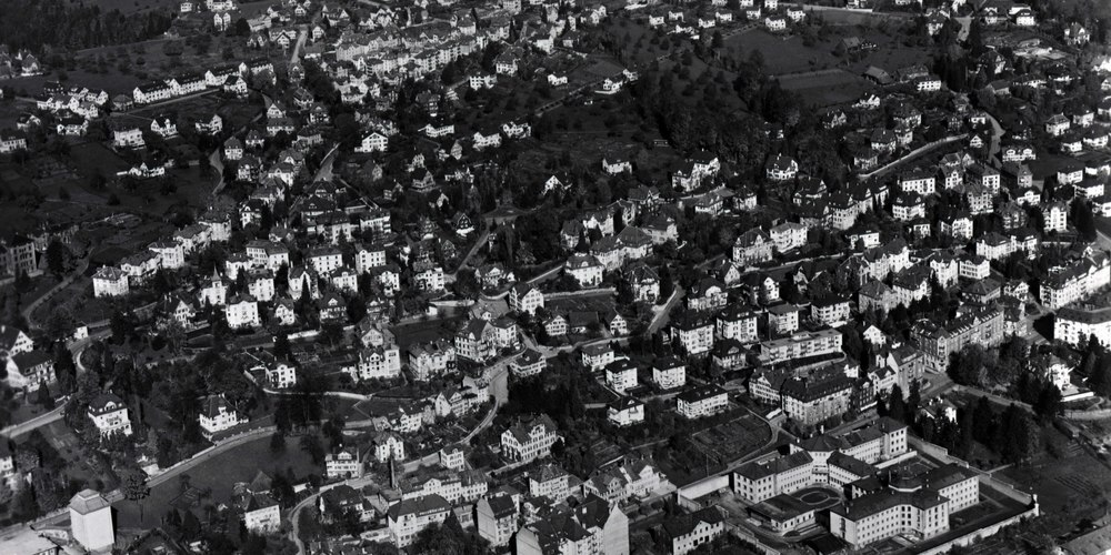 Ein Panoramablick auf das Quartier St. Jakob des Jahres 1945: Wir sehen den Schellenacker und die Viertel St.Jakob, Leimat sowie Rotmonten. Prägnant unten rechts im Bild die Strafanstalt St. Jakob (gebaut 1836-39, abgebrochen 1958). In der Bildmitte das alte Gebäude der Brauerei Schützengarten mit Kamin an der St. Jakob-Strasse 35 (gebaut 1884/85, abgebrochen 2000).