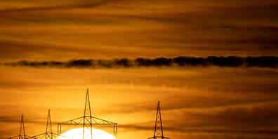 ARCHIV - Die Sonne geht hinter Hochspannungsmasten auf. Foto: Sebastian Gollnow/dpa