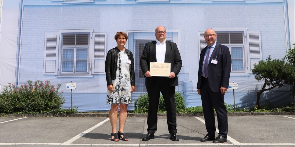 Thomas Harring (Mitte), CEO Leica Geosystems AG, durfte von der Balgacher Gemeindepräsidentin Silvia Troxler (links) die historische Baubewilligung aus dem Jahre 1921 als Geschenk zum Jubiläum entgegennehmen. Volkswirtschaftsdirektor Beat Tinner überbrachte die Glückwünsche der Regierung ebenfalls persönlich. 