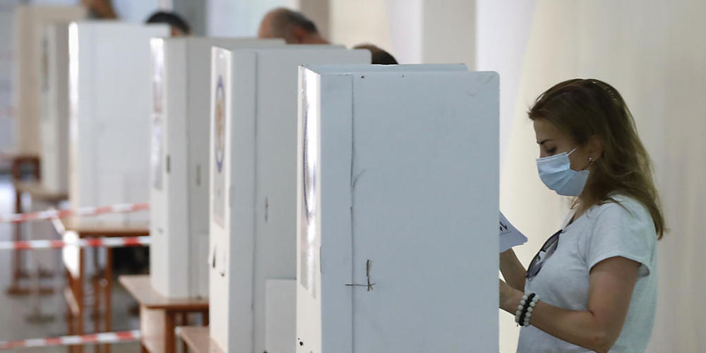 Menschen lesen während der Parlamentswahl in einem Wahllokal ihre Stimmzettel. Sieben Monate nach dem Krieg um die Konfliktregion Berg-Karabach wählt die krisengeschüttelte Südkaukasusrepublik Armenien ein neues Parlament. Foto: Sergei Grits/AP/dp...