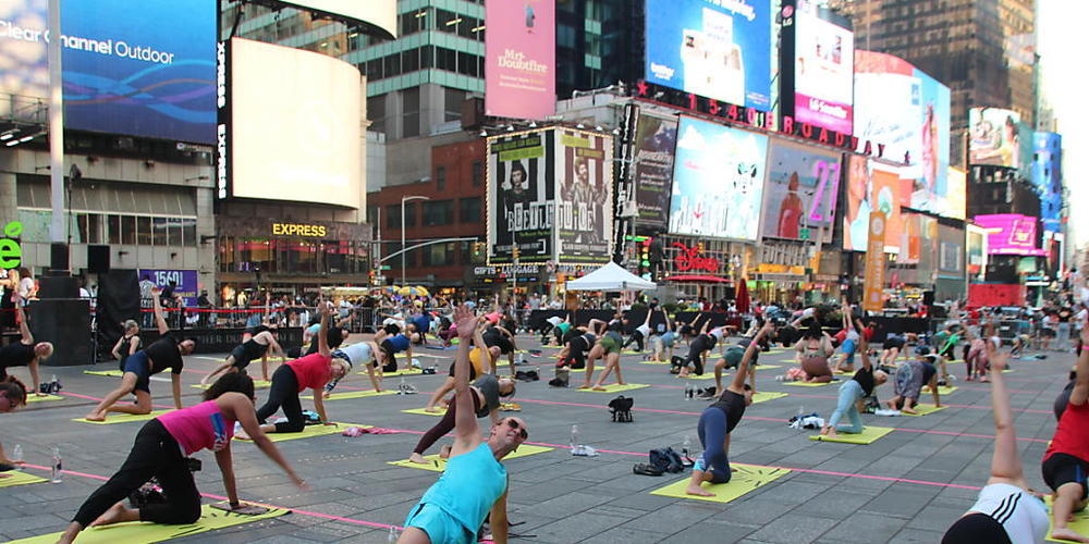 Menschen nehmen an einer gemeinsamen Yoga-Stunde inmitten des Times Square teil. Foto: Christina Horsten/dpa