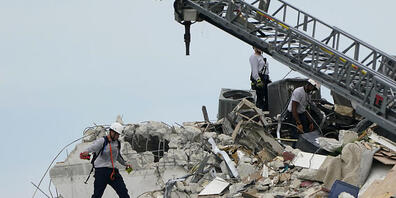 Rettungskräfte der Feuerwehr gehen durch die Trümmer einer Unfallstelle. Bei dem Teileinsturz eines mehrstöckigen Wohnhauses nahe Miami Beach ist mindestens ein Mensch ums Leben gekommen. Foto: Lynne Sladky/AP/dpa