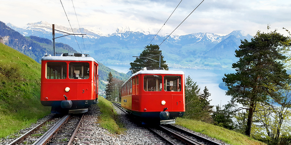 Die Motorwagen 1 und 3 der Rigi-Bahnen unterwegs zwischen Vitznau und Rigi Kaltbad mit Aussicht auf den Vierwaldstättersee.