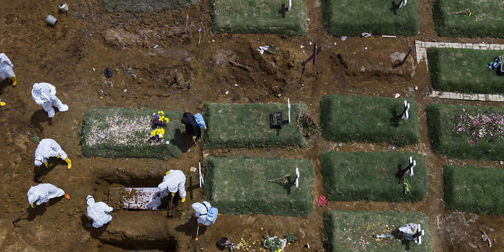 ARCHIV - Särge im indonisischen Medan werden auf einem speziell für Corona-Opfer vorgesehenen Friedhof zu Grabe getragen. Foto: Binsar Bakkara/AP/dpa
