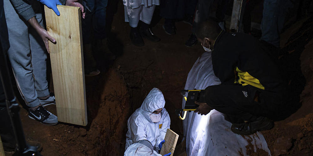 dpatopbilder - Menschen in Schutzkleidung nehmen in Johannesburg an einer Beerdigung einer an Corona gestorbenen Person teil. Südafrika ist eines der Länder auf dem Kontinent mit den meisten Todesfällen in Zusammenhang mit dem Coronavirus. Foto: A...
