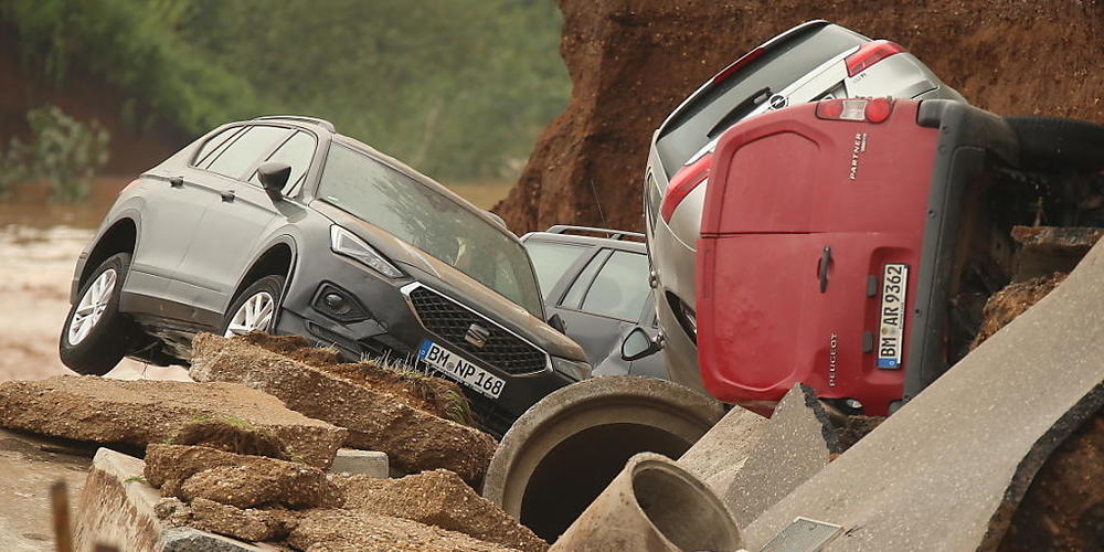 Autos liegen in einem ausgespülten Teil der nordrhein-westfälischen Stadt Erftstadt. Foto: David Young/dpa