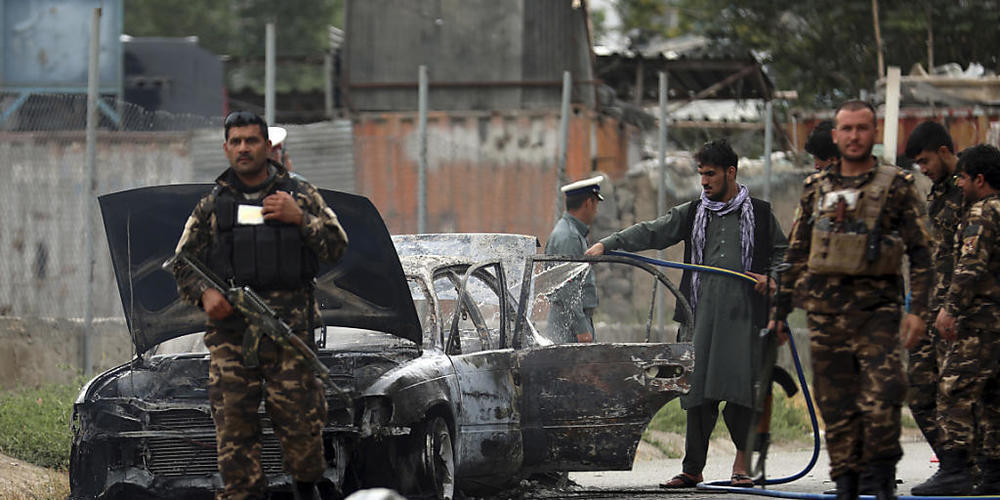 Sicherheitskräfte inspizieren das Wrack eines Fahrzeugs, das Raketen abgefeuert hat. Foto: Rahmat Gul/AP/dpa