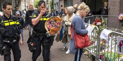 dpatopbilder - Polizisten bringen einen Blumenstrauß zu dem Blumenmeer für den Reporter Peter R. de Vries. Foto: Evert Elzinga/ANP/dpa