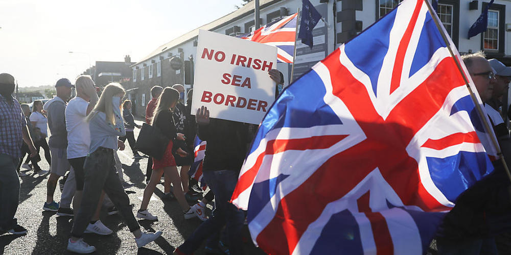 ARCHIV - Demonstranten halten britische Fahnen und ein Schild mit der Aufschrift «No Irish Sea Border» («Keine irische See-Grenze») bei einem Protest protestantischer Loyalisten gegen das sogenannte Nordirland-Protokoll. Foto: Brian Lawless/PA Wir...