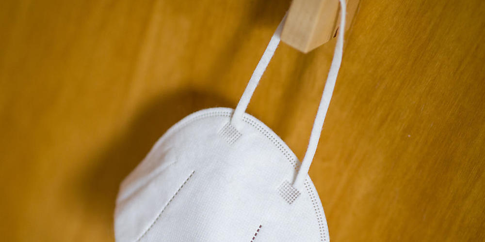 ARCHIV - Eine FFP2-Maske hängt an einem Haken. Foto: Daniel Karmann/dpa