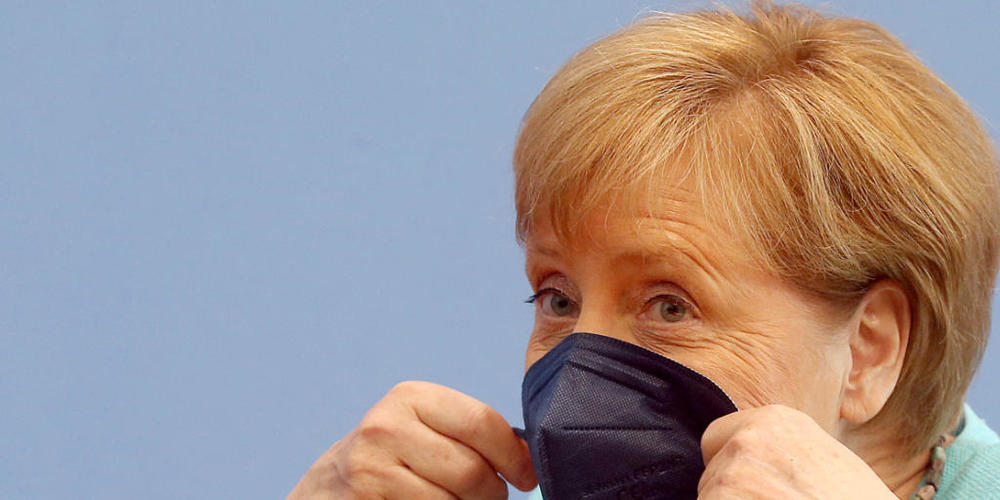 Bundeskanzlerin Angela Merkel (CDU) setzt sich ihre Maske auf. Foto: Wolfgang Kumm/dpa