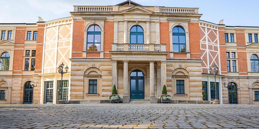Wolken ziehen über das Bayreuther Festspielhaus. Am 25.07.2021 beginnen die Bayreuther Festspiele. Foto: Nicolas Armer/dpa