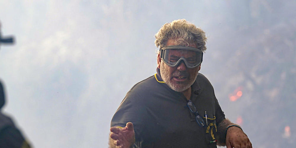 Ein Feuerwehrmann spricht bei Löscharbeiten mit seinem Kollegen. Foto: Alessandro Tocco/LaPresse via AP/dpa