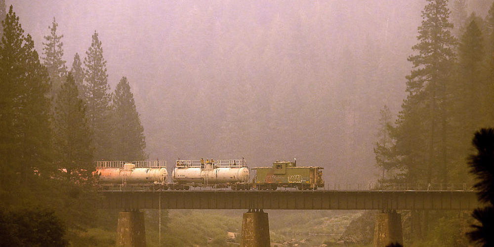 Ein Löschzug versprüht in Plumas County Löschmittel auf Gleise und umliegendes Land. Foto: Noah Berger/AP/dpa
