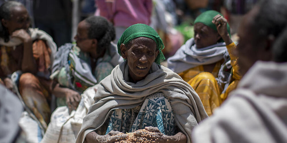 ARCHIV - Eine äthiopische Frau schaufelt Weizenkörner auf, nachdem diese von der "Relief Society of Tigray" im Norden Äthiopiens verteilt wurden. (Archivbild) Foto: Ben Curtis/AP/dpa