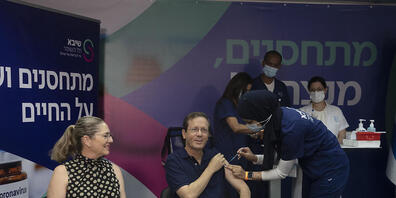 Izchak Herzog (M), Staatspräsident von Israel, erhält eine dritte Impfung gegen das Coronavirus, während seine Frau Michal (l) zusieht. Foto: Maya Alleruzzo/POOL AP/dpa