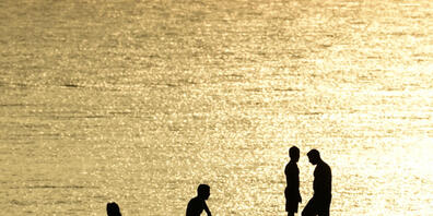 Menschen stehen auf Felsen in der Nähe eines Strandes im Vorort Kavouri. Die extreme Hitzewelle in Griechenland lässt nicht locker. Seit über einer Woche klettern die Temperaturen für mehrere Stunden täglich auf über 40 Grad. Foto: Michael Varakla...