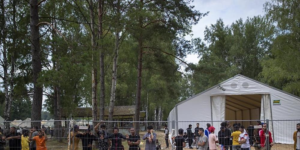 Geflüchtete stehen hinter einem Zaun des neu errichteten Flüchtlingslagers auf dem Truppenübungsplatz Rudninkai, etwa 38 km südlich von Vilnius. Das Rote Kreuz kritisierte die Entscheidung der litauischen Regierung, Migranten aus Belarus abzuweise...