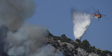 Ein Hubschrauber wirft über einem Feuer in der Nähe des Dorfes Malakasa nördlich von Athen Wasser ab. Foto: Petros Karadjias/AP/dpa