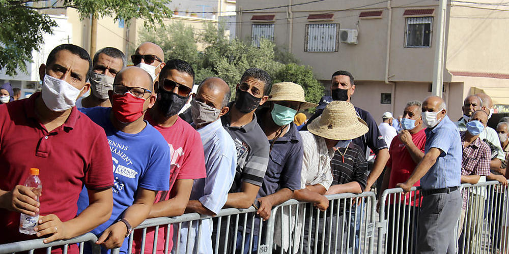 Einwohner des Ortes Oued Ellil warten vor einer Schule, um sich während einer Impfaktion mit dem Corona-Impfstoff Vaxzevria impfen zu lassen. In Tunesien sind laut Angaben des Gesundheitsministeriums bei einer landesweiten Impfaktion gut 550 000 M...