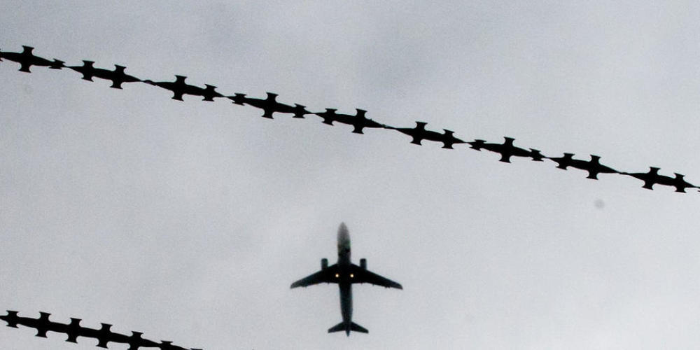 ARCHIV - Symbolbild: Ein Flugzeug ist hinter Stacheldraht zu sehen. Foto: Julian Stratenschulte/dpa