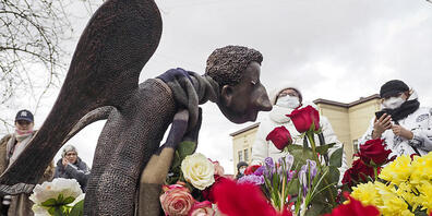 ARCHIV - Menschen stehen vor der mit Blumen umringten Skulptur «Trauriger Engel» des Bildhauers Shustrov, während der Eröffnung einer Gedenkstätte für medizinische Mitarbeiter, die in St. Petersburg an einer Corona-Infektion gestorben sind (Archiv...