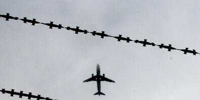 ARCHIV - Ein Flugzeug ist hinter Stacheldraht zu sehen. Foto: Julian Stratenschulte/dpa
