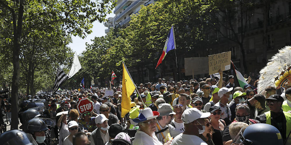 Demonstranten halten Fahnen und Schilder bei einem Protest gegen die Corona-Regeln. Der Unmut der Demonstranten richtet sich gegen die Impfpflicht für Gesundheitspersonal und gegen jüngst von der französischen Regierung beschlossene verschärfte Na...