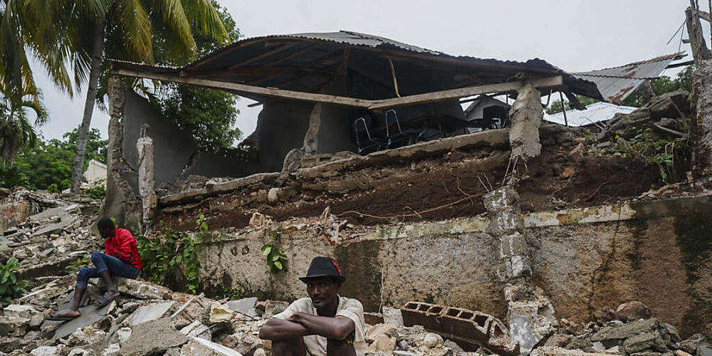 Ein Mann hockt auf den Trümmern des durch das Erdbeben zerstörten Krankenhauses in Fleurant. Die vorläufige Zahl der Erdbeben-Todesopfer in Haiti ist noch einmal deutlich gestiegen. Die haitianische Zivilschutzbehörde meldete am Dienstag via Twitt...