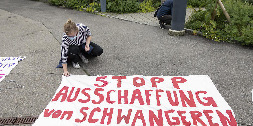 Eine Aktivistin sichert vor dem Gebäude des Staatssekretariats für Migration ein Transparent mit einem Stein, damit es nicht fortgeblasen wird.