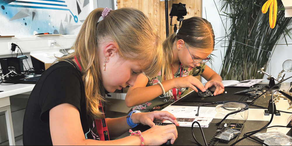 Mila (l.) und Julia arbeiten konzentriert am Löten ihrer Roboter.