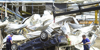 Menschen entfernen Trümmer neben einem Autowrack. Nach dem verheerenden Tornado im Südosten Tschechiens haben die Aufräumarbeiten begonnen. Foto: Perina Ludek/CTK/AP/dpa