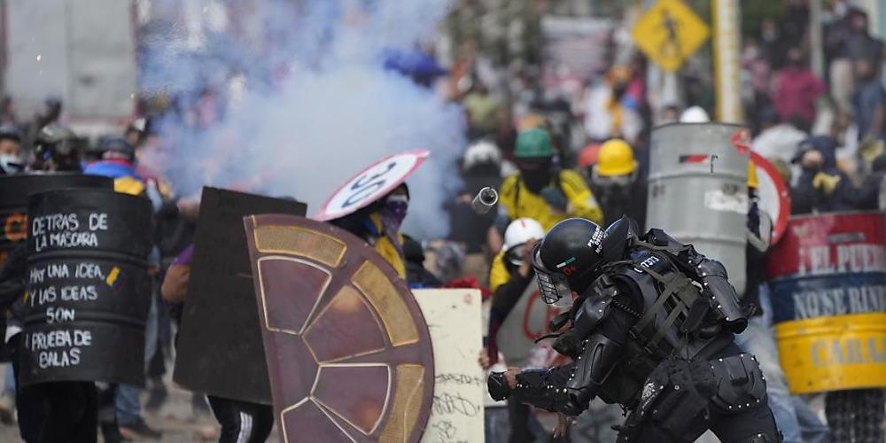 Ein Polizist wirft eine Blendgranate auf Demonstranten während anhaltender Anti-Regierungs-Proteste, die durch vorgeschlagene Steuererhöhungen auf öffentliche Dienstleistungen, Kraftstoff, Löhne und Renten in Bogota, Kolumbien, ausgelöst wurden. F...