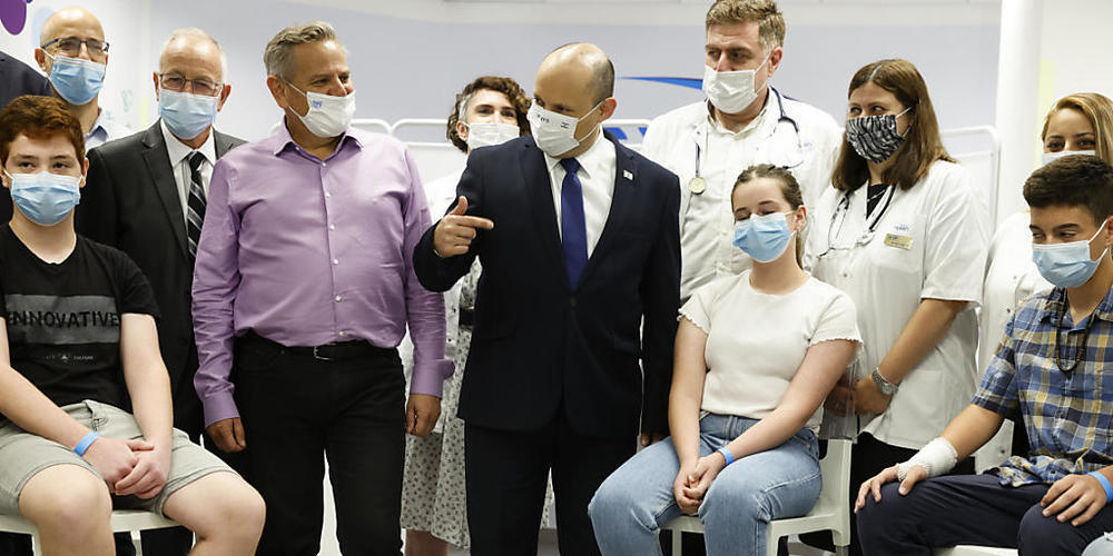 Naftali Bennett (M), Ministerpräsident von Israel, beim Besuch einer Maccabi Healthcare Maintenance Organisation (HMO), die Impfungen gegen das Coronavirus anbietet. Foto: Amir Cohen/Reuters Pool/AP/dpa