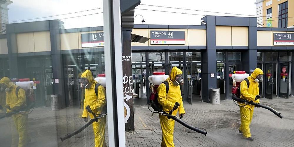 Mitarbeiter des Katastrophenschutzes desinfizieren einen Bahnsteig des Sawjolowski-Bahnhofs in Moskau. Foto: Alexander Zemlianichenko/AP/dpa