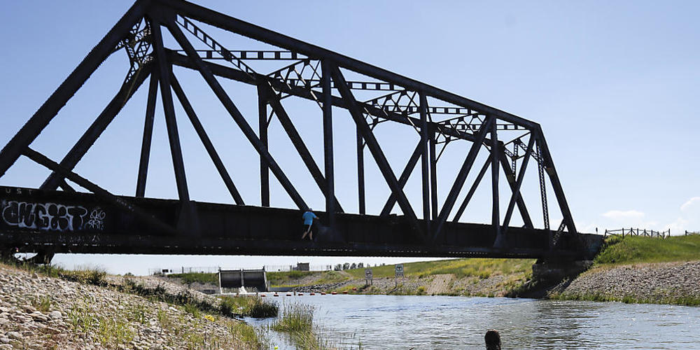 Junge Leute kühlen sich in einem Bewässerungskanal ab. Die anhaltende Hitzewelle im Westen Kanadas hat für neue Höchsttemperaturen gesorgt und zu mehreren Todesfällen beigetragen. Foto: Jeff Mcintosh/The Canadian Press/AP/dpa Foto: Jeff Mcintosh/T...