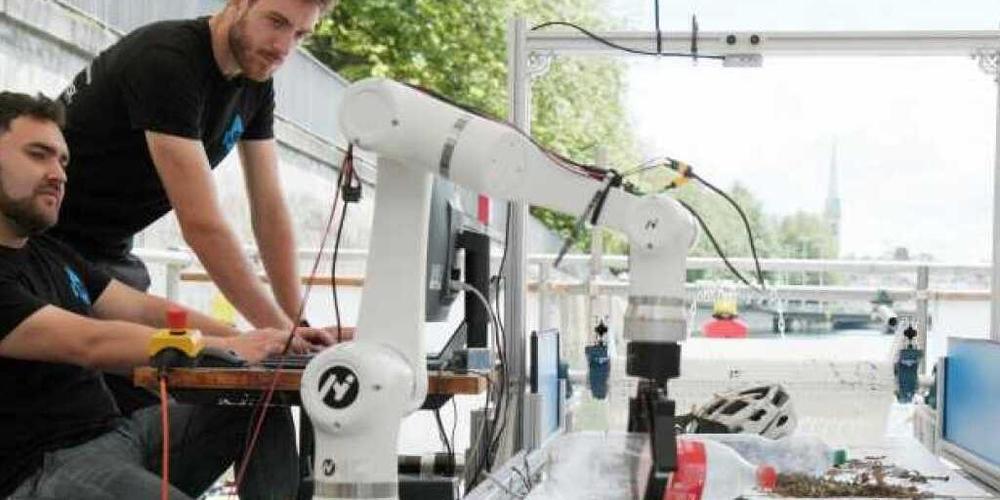 Zwei ETH-Studierende auf der "Autonomous River Cleanup"-Plattform, auf der Abfälle aus der Limmat quantifiziert und sortiert werden. Ein Roboterarm mit Kamera trennt die Abfälle nach Material, Biomasse wird in den Fluss zurückbefördert (Bild ETH).