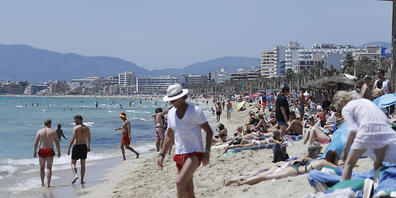 Touristen halten sich am Strand von Arenal in Palma de Mallorca auf. Foto: Clara Margais/dpa