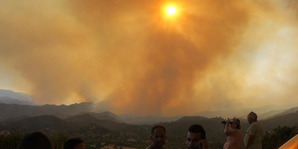 Anwohner beobachten ein Feuer in der Bergregion von Larnaca. Foto: Petros Karadjias/AP/dpa
