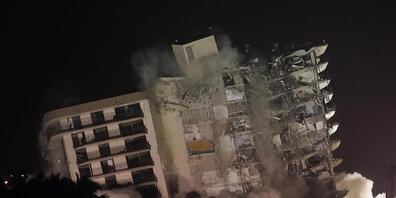 Die beschädigte Reststruktur des Champlain Towers South Condo Gebäudes stürzt ein. Nach dem Teileinsturz des Wohnkomplexes in der Nähe von Miami ist der noch stehende Gebäudeteil gesprengt werden. Die Ruine war instabil. Foto: Lynne Sladky/AP/dpa ...