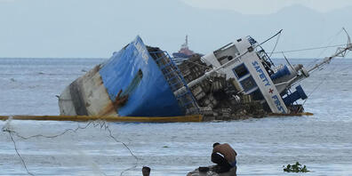 Ein Fischer wirft sein Netz neben der halb gesunkenen Frachtschiff MV Palawan Pearl aus. Nach einer Schiffskollision vor der Küste der Philippinen befürchten die Behörden eine mögliche Ölkatastrophe. Foto: Aaron Favila/AP/dpa
