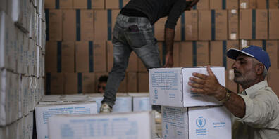 ARCHIV - Zwei Syrer räumen humanitäre Hilfsgüter des Welternährungsprogramms ein. Foto: Anas Alkharboutli/dpa